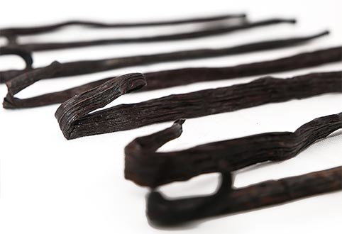 Natural dark vanilla beans lined, with their curled edges to the front.
